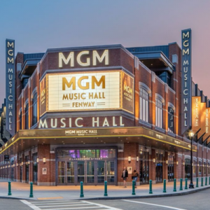 Exterior view of MGM Music Hall at Fenway, illuminated at night, with concertgoers gathered outside.